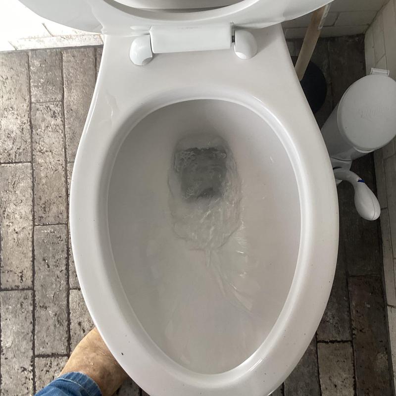 Toilet bowl unclogging with auger in bathroom