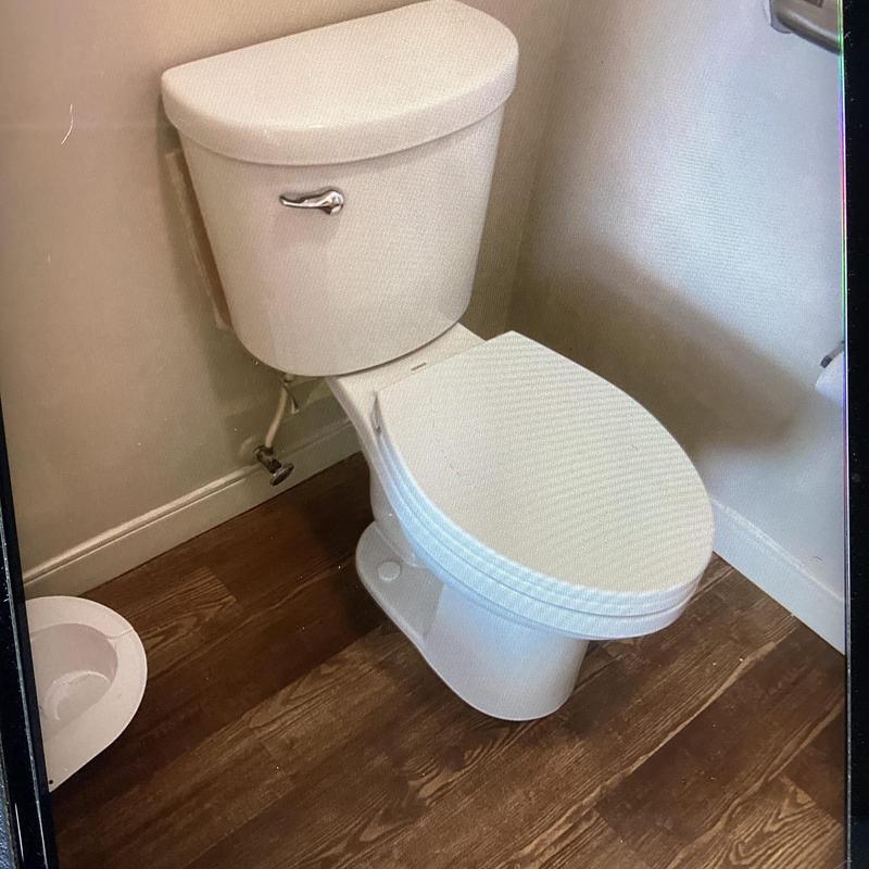 Toilet replacement in residential bathroom with wood flooring