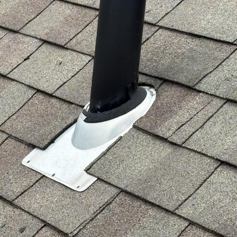 Plumbing vent boot on shingled roof with repairs