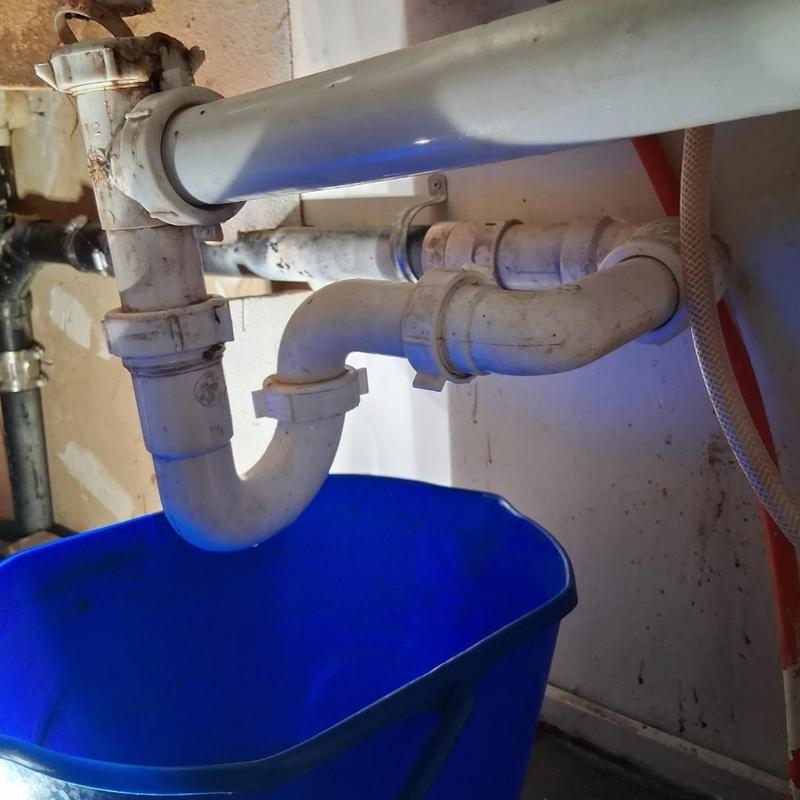 Kitchen sink drain pipes with blue bucket below