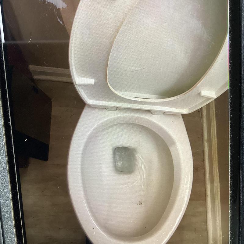 Toilet bowl with flushing water in bathroom