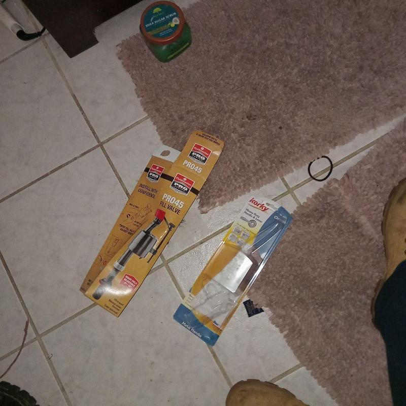 Fill valve and flush handle packaging on tiled floor Fill valve and flush handle packaging on tiled floor