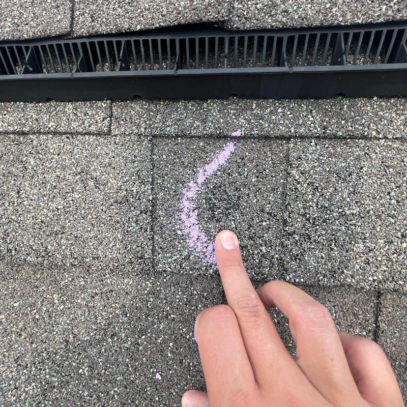 Shingle damage with chalk marking near roof vent