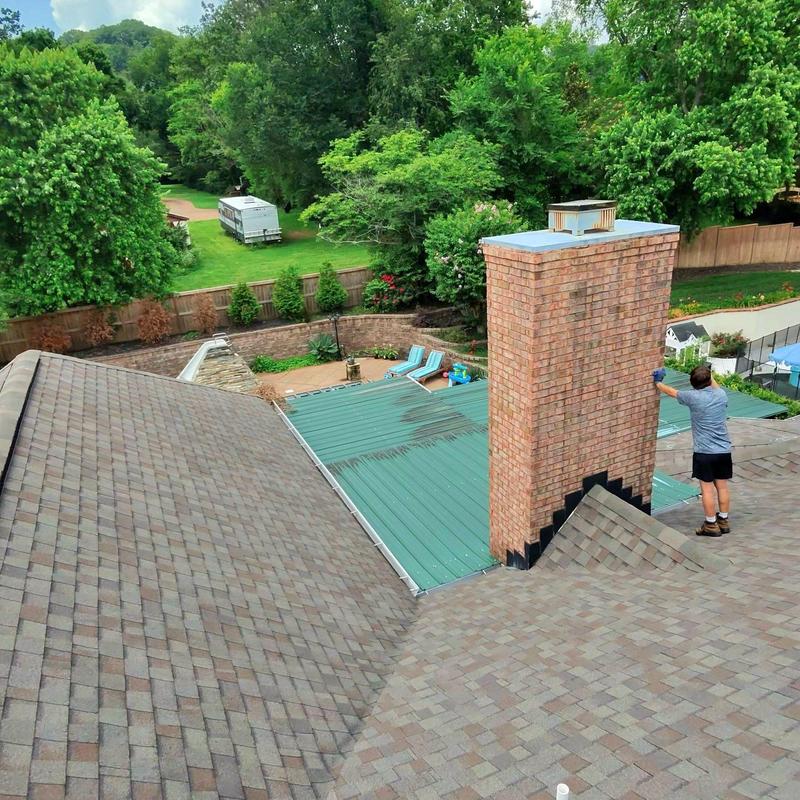 Brick chimney with roof shingles and metal roofing panel inspection
