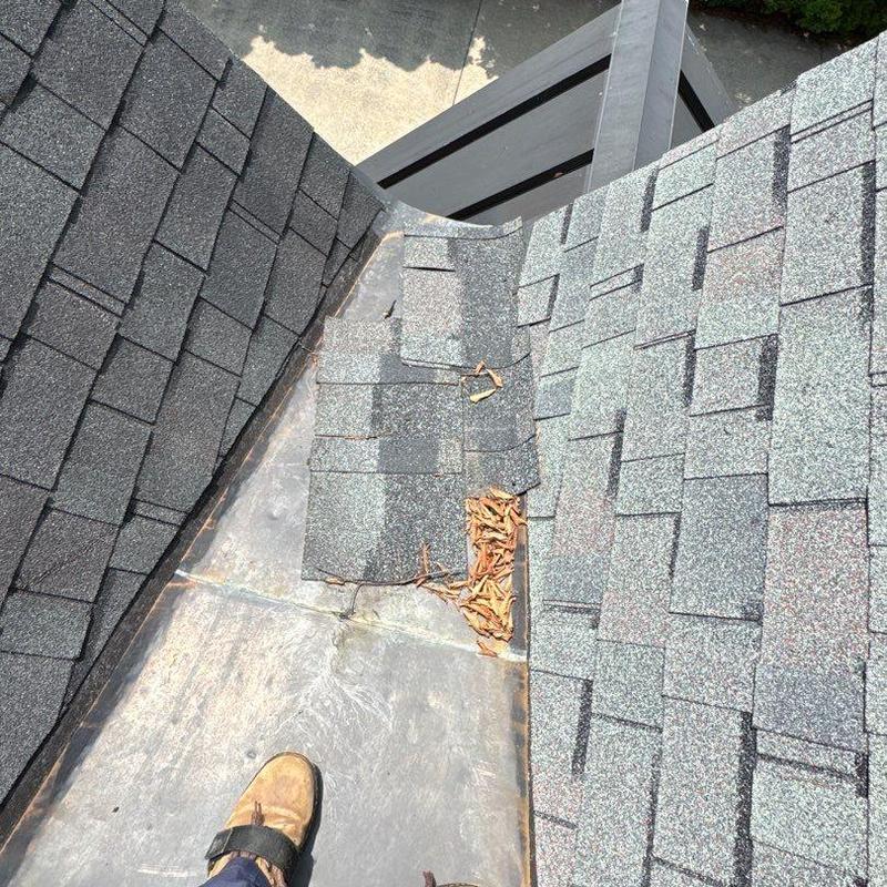 Roof valley flashing with damaged shingles and debris