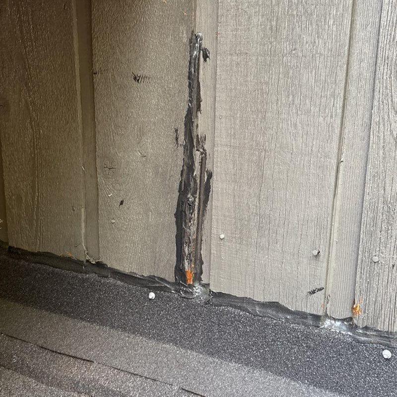 Wood siding with sealant repair near roof edge