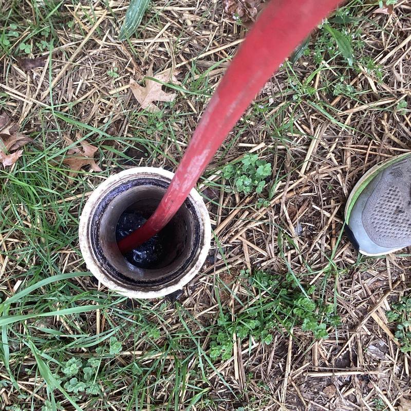 Jetted sewer cleanout line with red hose outdoors