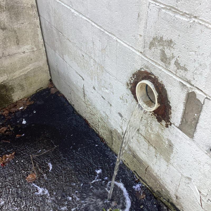 Sewer line discharge pipe with flowing water outside wall