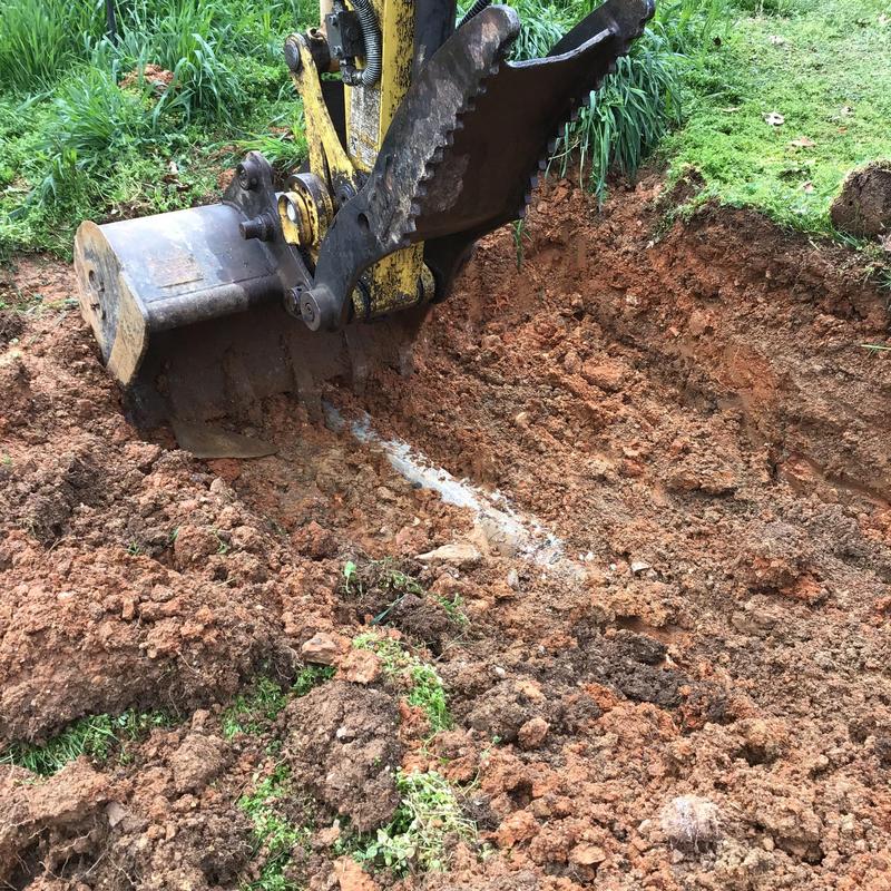 Field water line excavation with backhoe digging dirt