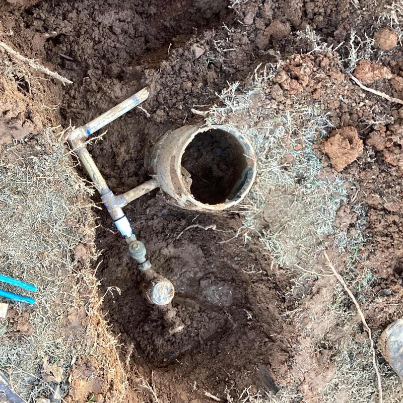 Water meter with exposed piping in dirt hole