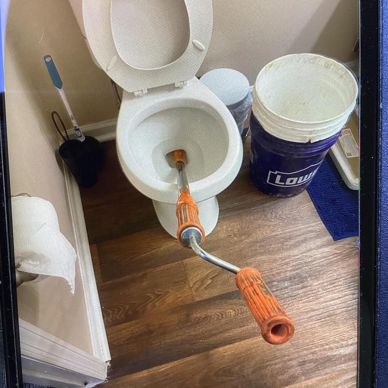 Toilet clog with auger tool in residential bathroom