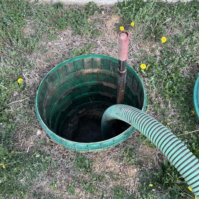Septic tank riser with pump hose inserted outdoors