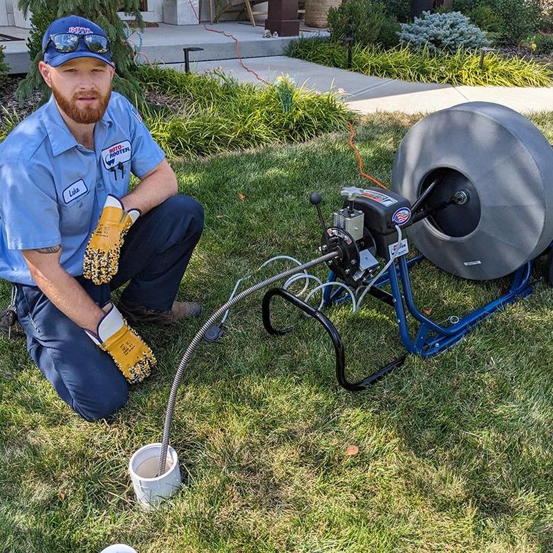 Sewer drain cleaning machine with plumber in lawn