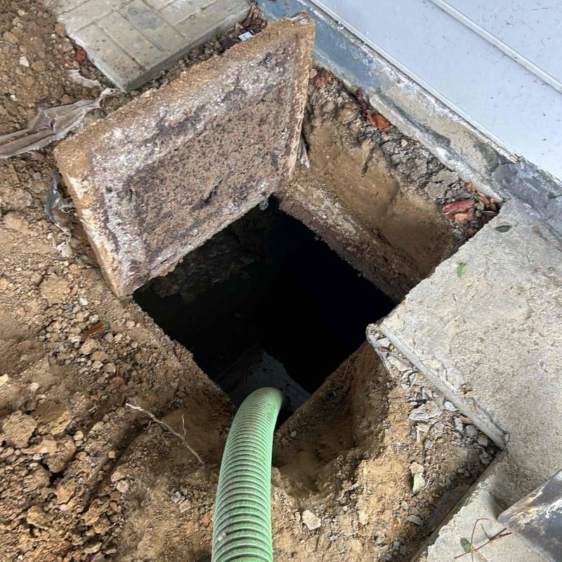 Septic tank with pumping hose in ground opening