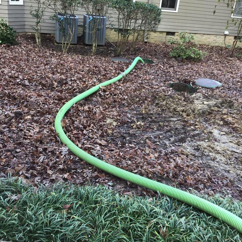 Septic tank riser with green pump hose outdoors