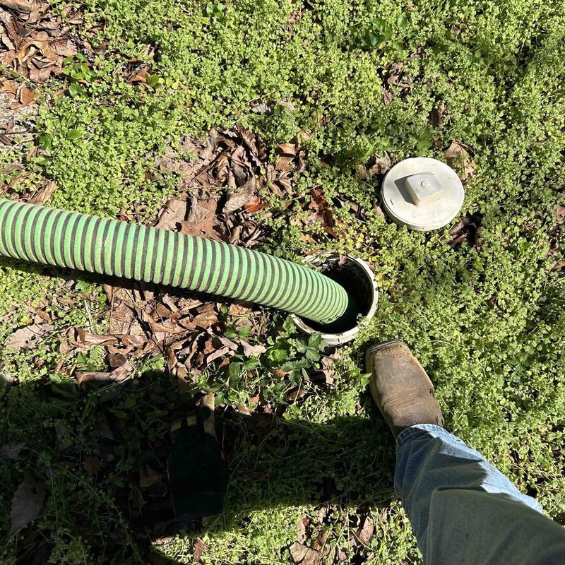 Septic tank riser with green hose for pumping