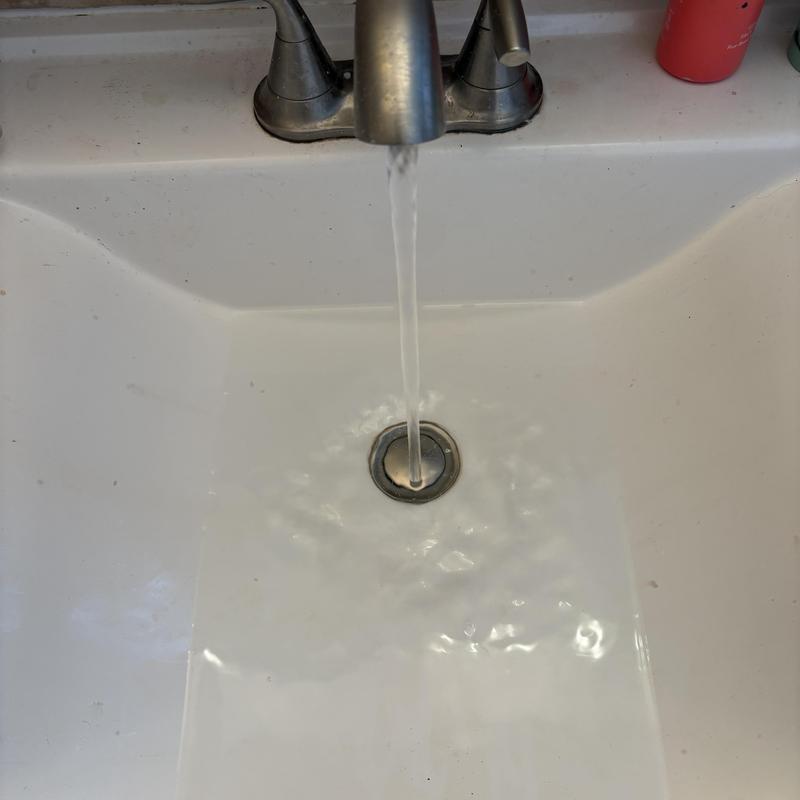 Bathroom sink basin drain with flowing water