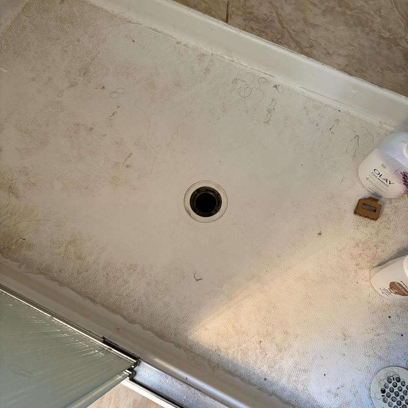 Shower drain clog with dirt buildup in shower pan