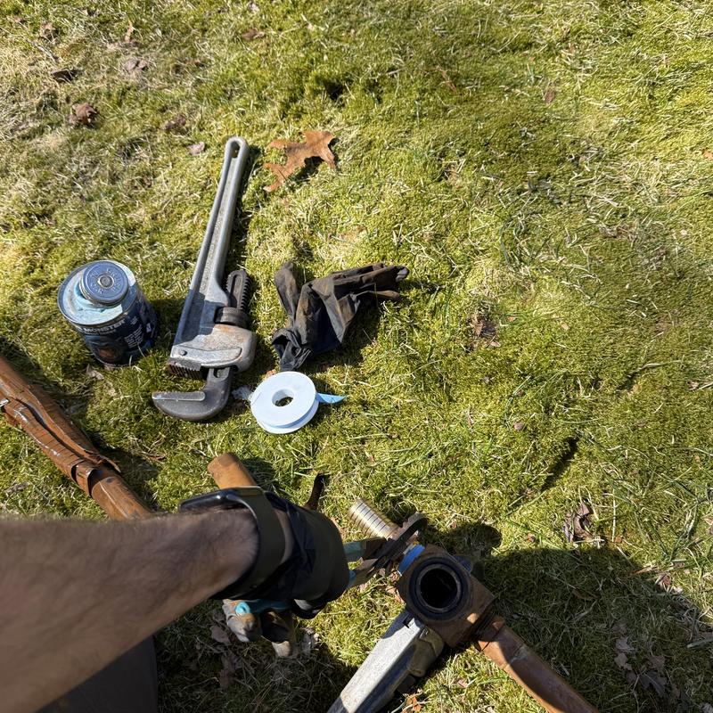 Well pump pipe connection with wrench and gloves on grass Well pump pipe connection with wrench and gloves on grass