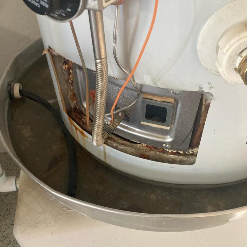 Water heater leak pan filled with water and rust