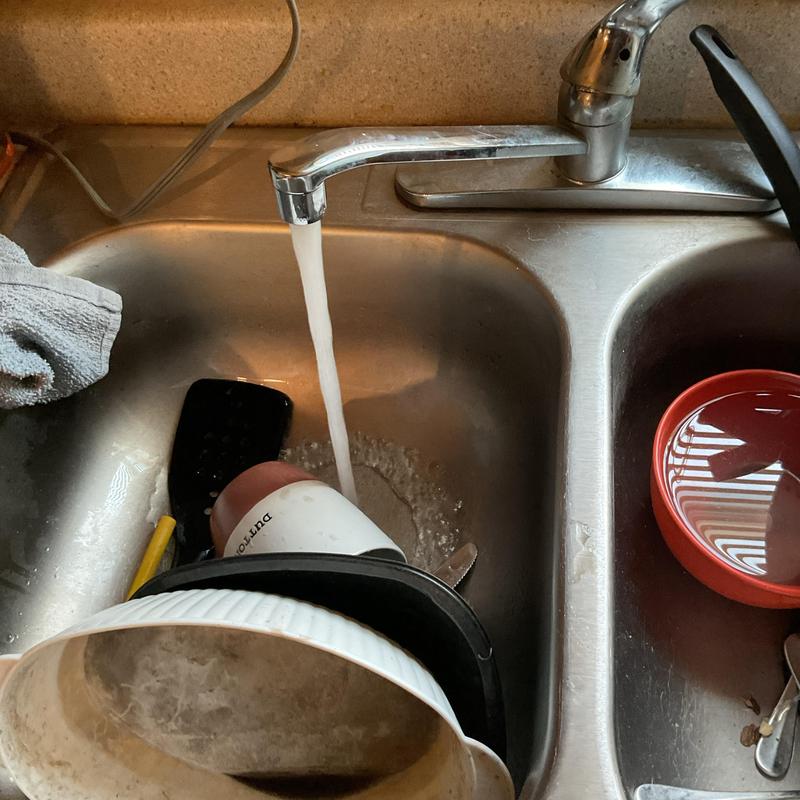 Kitchen sink drain with running water and dishes Kitchen sink drain with running water and dishes