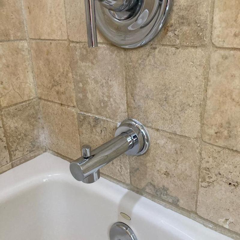 Chrome tub spout and handle on tiled bathroom wall Chrome tub spout and handle on tiled bathroom wall