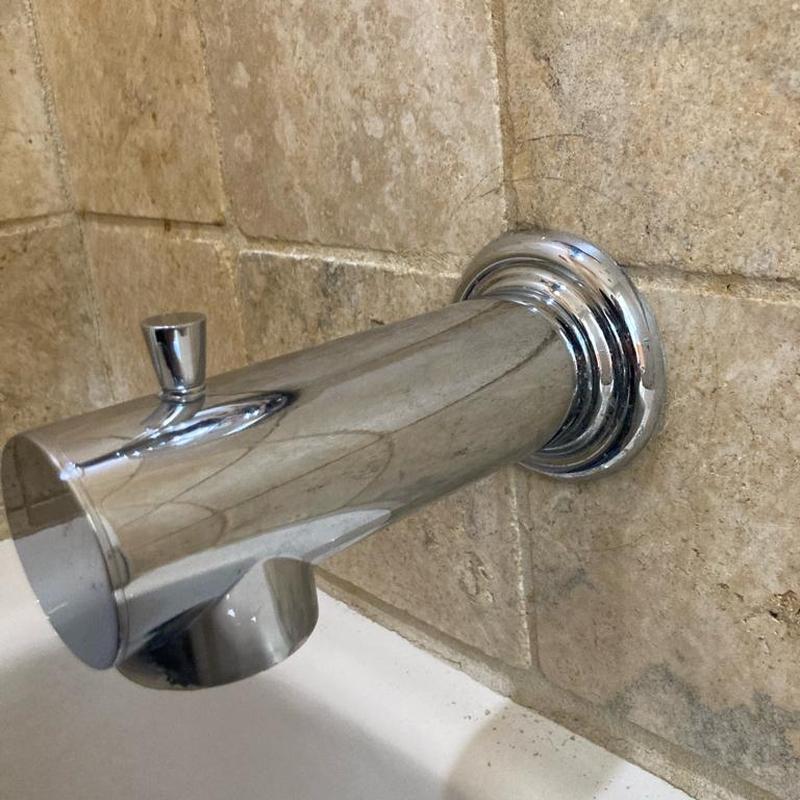 Chrome bathtub spout installed on tiled bathroom wall Chrome bathtub spout installed on tiled bathroom wall