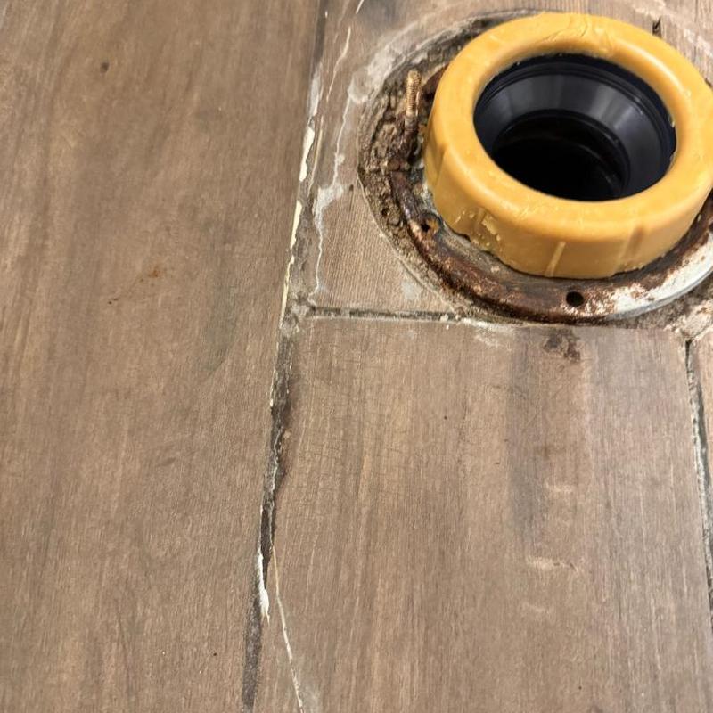 Toilet flange with surface rust on tile floor Toilet flange with surface rust on tile floor