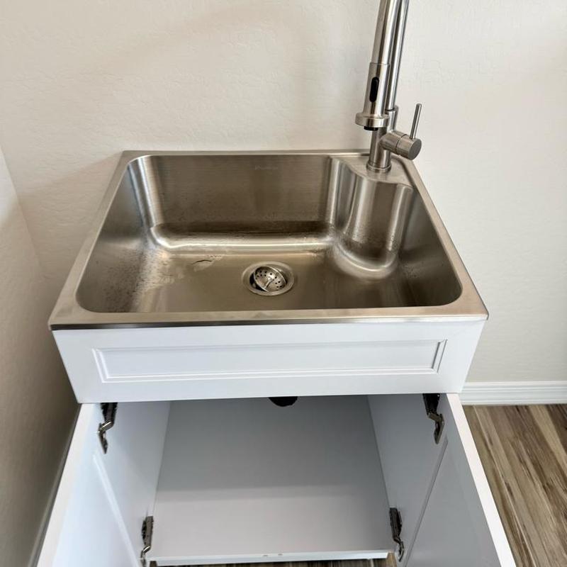 Laundry sink with stainless faucet and cabinet open
