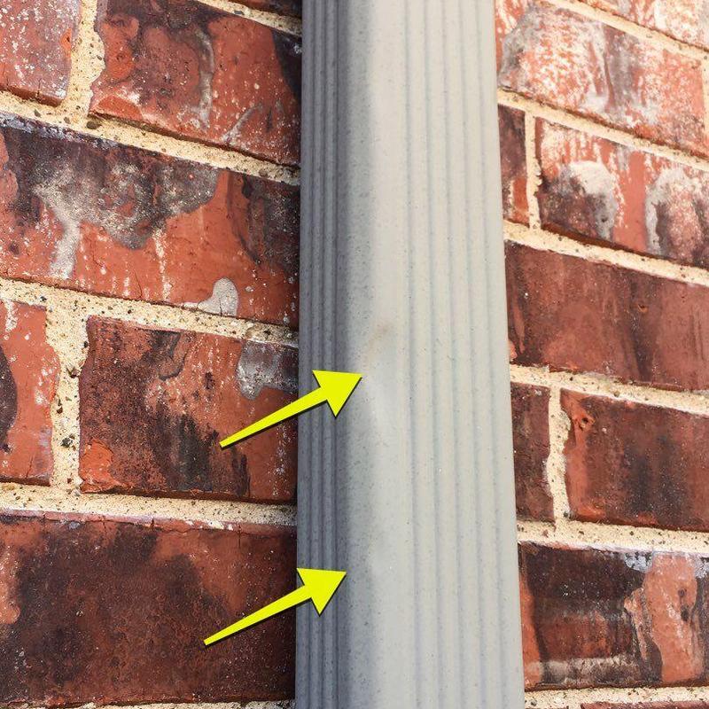 Downspout dents on brick wall background with yellow arrows Downspout dents on brick wall background with yellow arrows