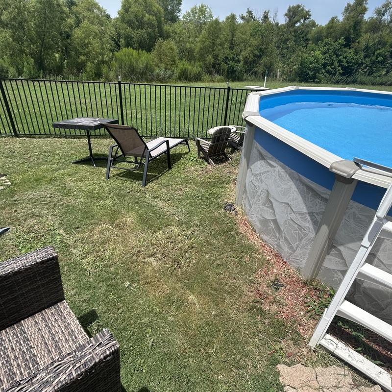 Above ground pool with lawn chairs in backyard