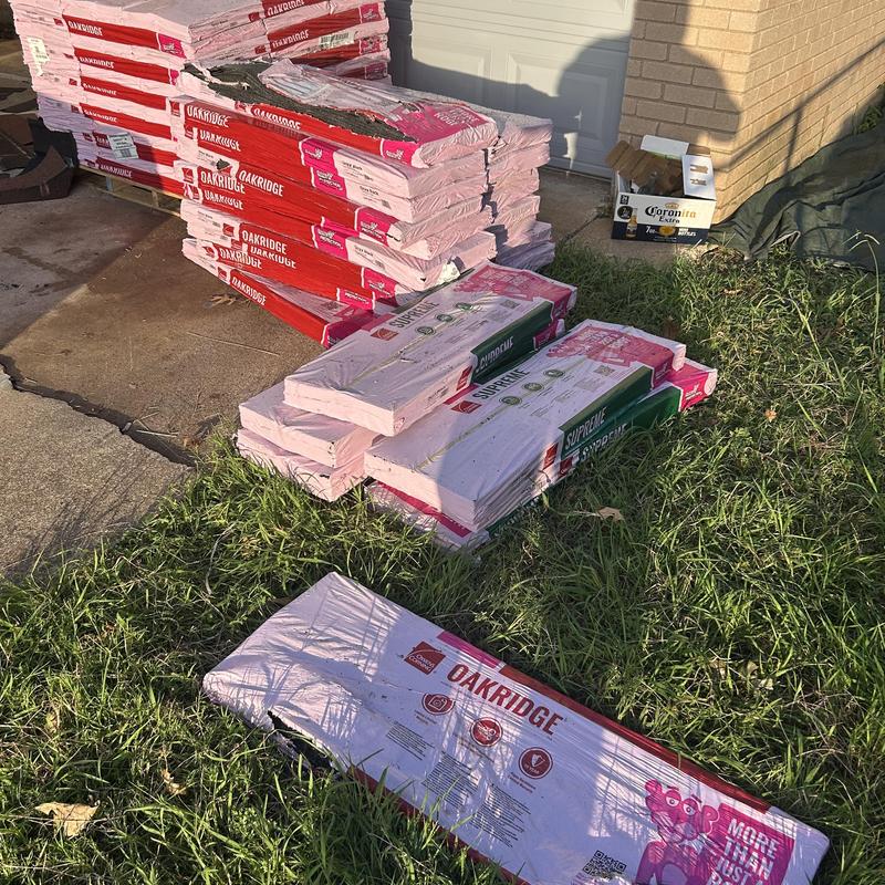 Oakridge roofing shingles stacked outdoors on grass