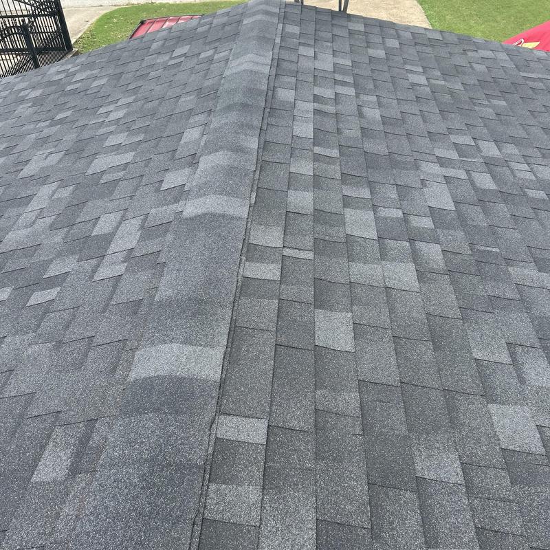 Gray asphalt shingle roof with ridge cap installation
