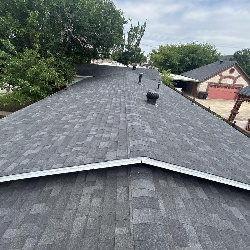 Black asphalt shingle roof with ridge vent installation