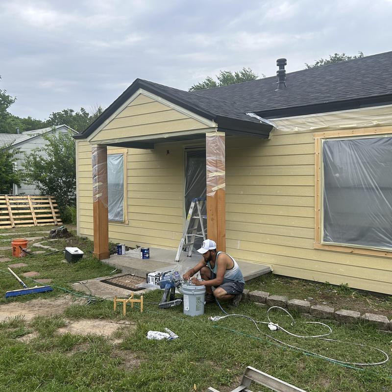 Siding installation on yellow house exterior in progress