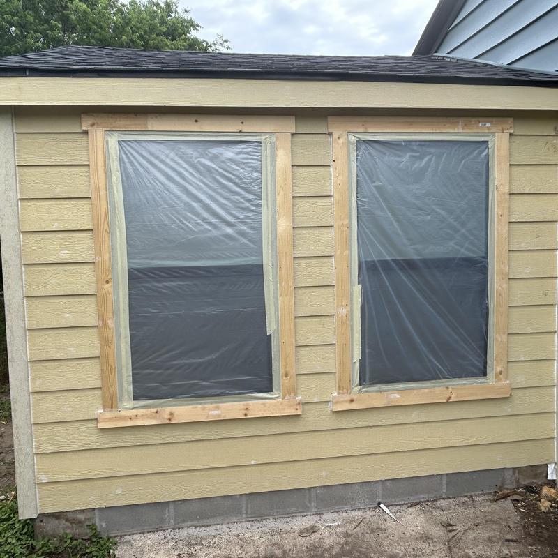 Siding with window openings covered in plastic film