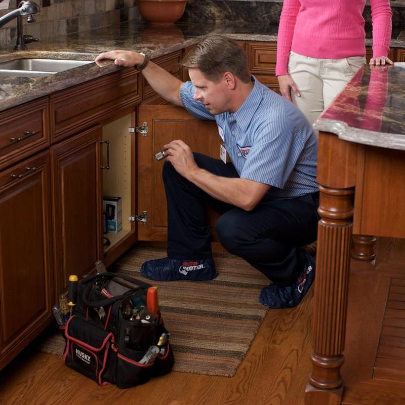 Kitchen cabinet plumbing inspection with tool bag nearby