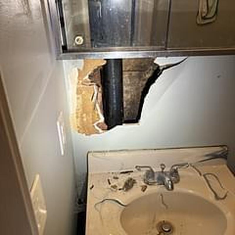 Bathtub drain pipe visible through ceiling access hole