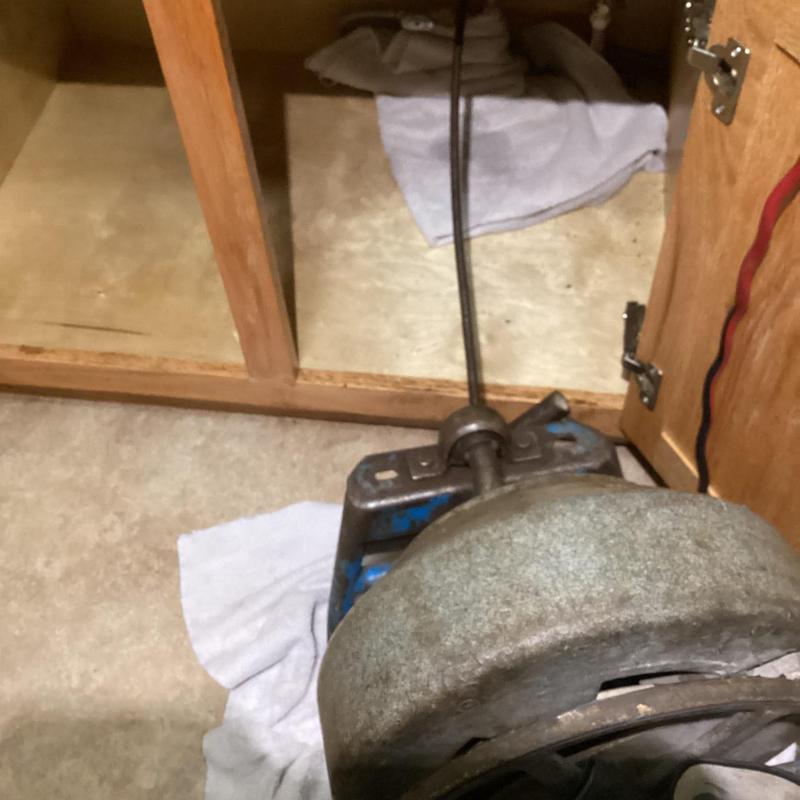 Kitchen sink drain clog with plumbing snake inside cabinet