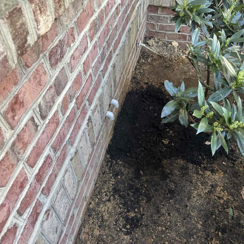 Underground plumbing line excavation near house foundation