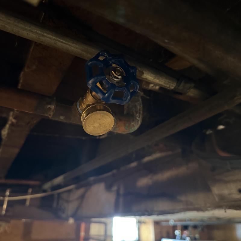 Boiler drain valve with blue handle in basement piping