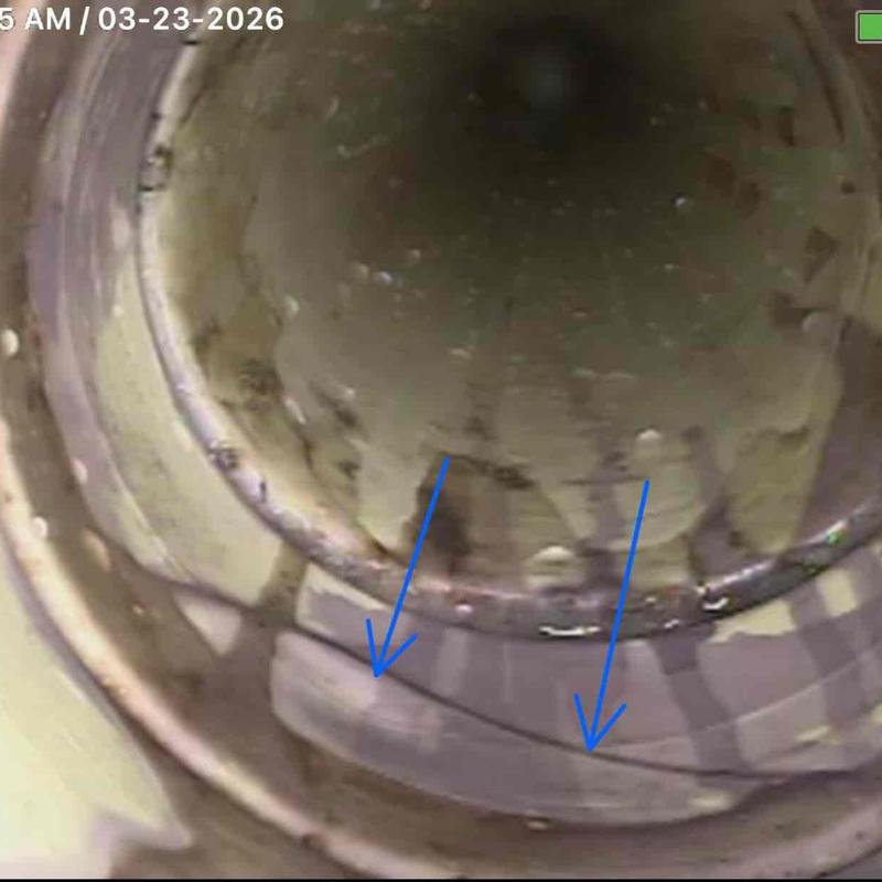 Sewer pipe interior with visible cracks marked by arrows