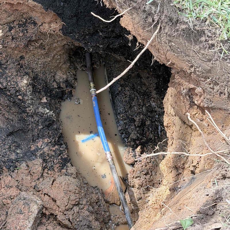 Blue water pipe in muddy excavation trench