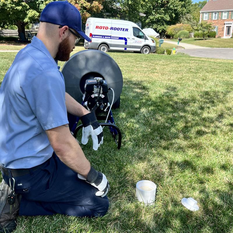 Commode auger with plumber operating in lawn