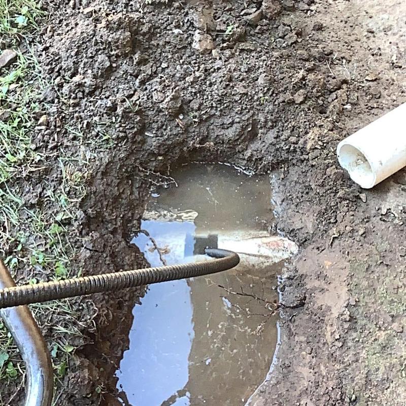 Septic tank main line with drain snake in muddy hole