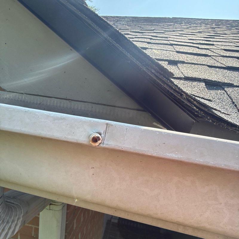Roof gutter with rusted screw near shingle edge