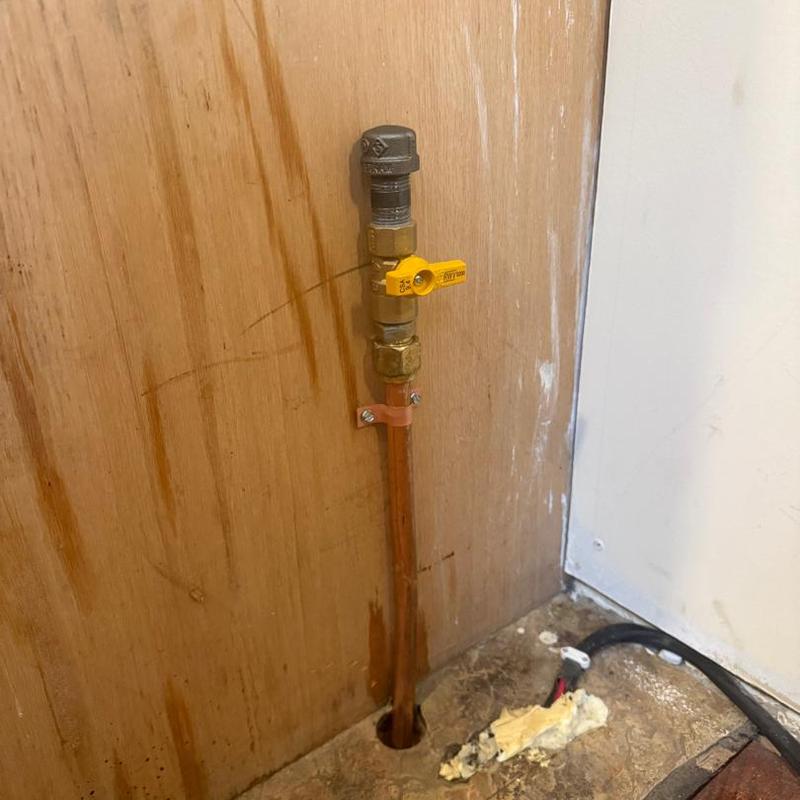 Gas line valve with yellow handle on wooden wall