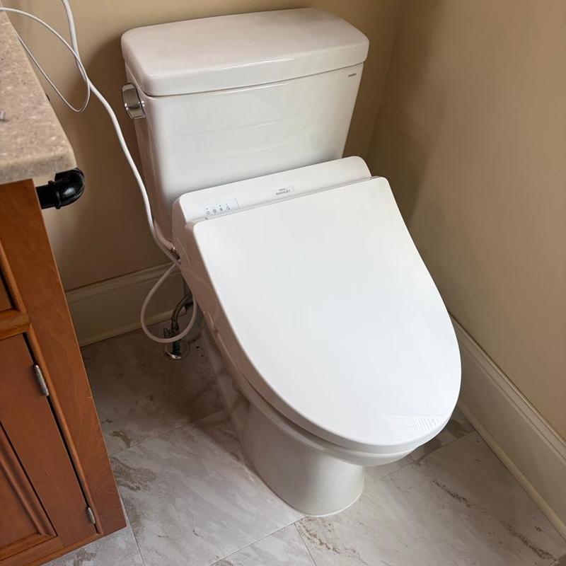 Toilet with bidet seat installed in bathroom corner
