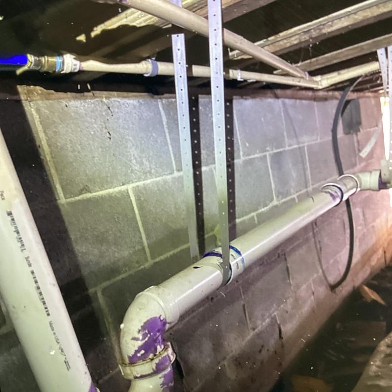 PVC plumbing pipe supported in crawl space basement