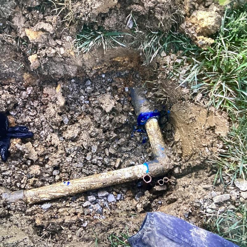 Copper water pipe joint with blue sealant in dirt